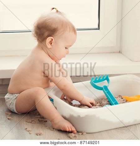 Little Girl Playing With Sand On Floor