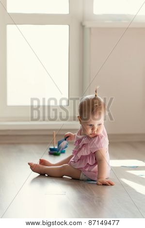 Little Girl Playing With Pyramid On Floor