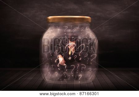 Businessman locked into a jar with question marks concept on background