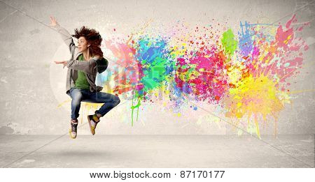 Happy teenager jumping with colorful ink splatter on urban background concept