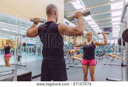 Man coach training to woman with dumbbells exercises