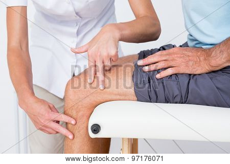 Doctor examining her patient knee in medical office