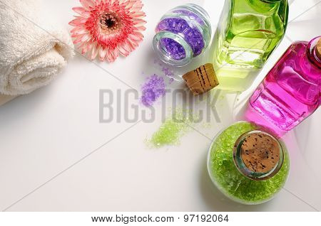 Oils And Bath Salts On White Glass Table Top View