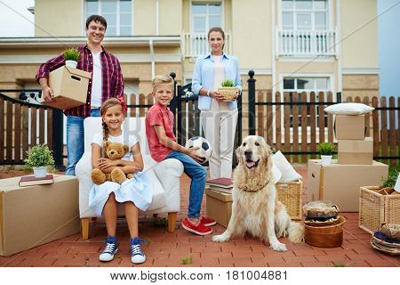 Young couple and their kids gathered in front of new cottage before settling