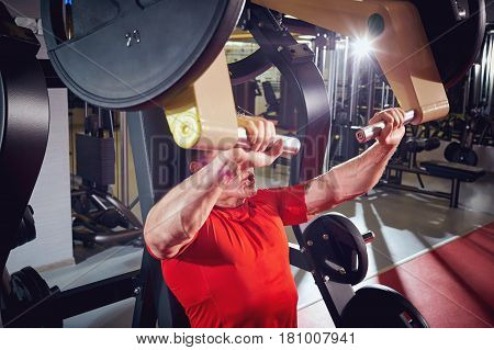 Man sports doing exercise on  simulator in the gym.