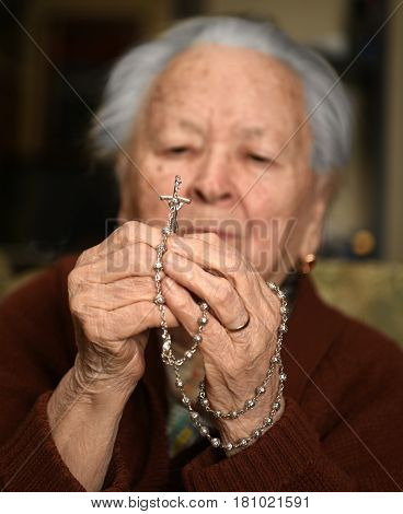 Old Woman Praying And  Holding Silver Rosary