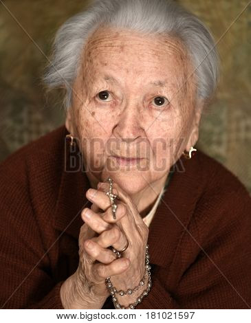 Old Woman Praying And  Holding Silver Rosary