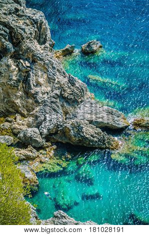 Tourists shorkling between Rocks in Azure Bay of Beautiful Paleokastritsa in Corfu Island, Greece. Vertical orientation