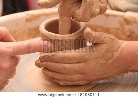 hands of a potter, creating an earthen jar on a pottery wheel