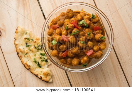 spicy chick peas curry or Chola Masala or Chana Masala or chole bhature or choley garnished with sliced onion and green coriander leaf, selective focus