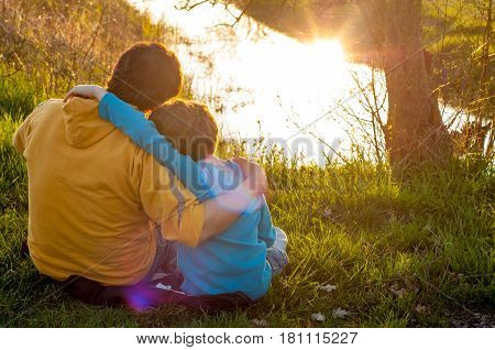 Father and son are hugging at the pond