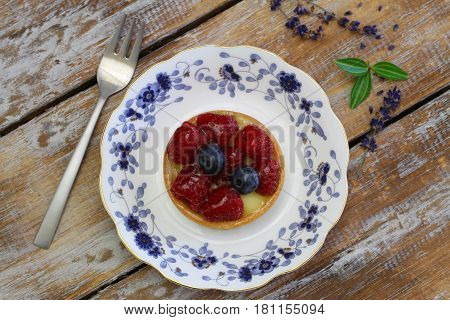 Crunchy tartelette with fresh fruit on vintage plate on rustic wood