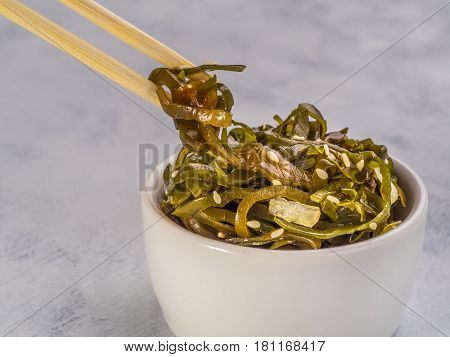 Close up view of kelp seaweed salad with sesame seeds on gray concrete background. Copy space.