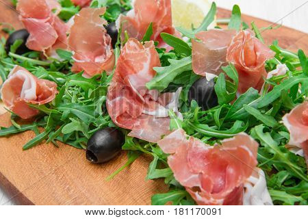 Chopping Board With Aragula And Raw Ham