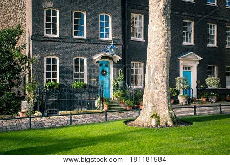 An Old Brick House With A Plot Of Green Grass And Tree