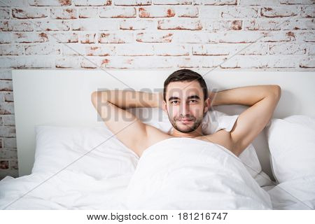 Handsome Well Built Man Resting In His Bed On Brick Wall In Room At Home