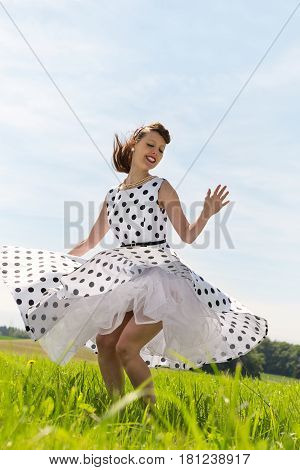 pretty Rockabilly Girl with a petticoat dress is dancing rock & roll on the meadow