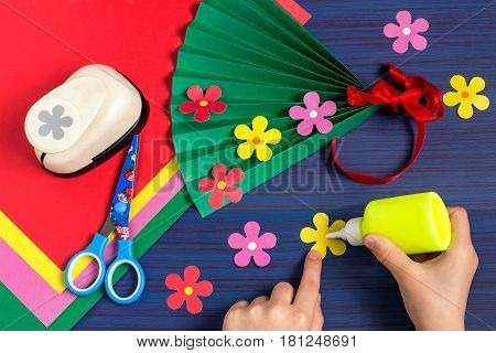 Making gift for Mother's Day by the child. Colorful bouquet of flowers out of paper. Children's art project. DIY concept. Step-by-step photo instruction. Step 6. Child glues flowers on a fan