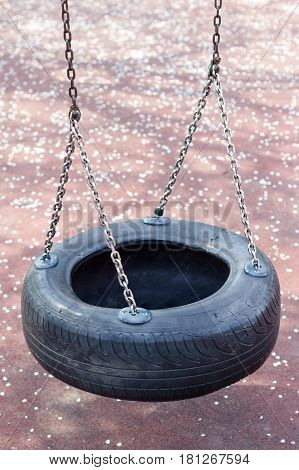 top view close up of children black rubber tire swing wheel hanging on metallic chains