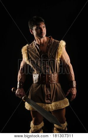 The caveman is in the dark with a sword.