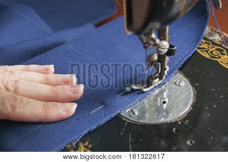 Sewing mashine with human hand pressing the blue tissue