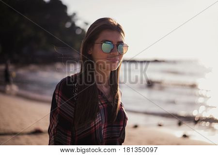 young stylish happy hipster woman traveling around the world wearing aviator sunglasses, denim shirt, tropical island lagoon vacation.