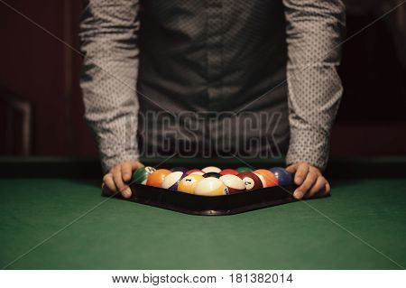 American billiard poule. Triangle of billiard balls. A man getting ready to start a game of billiards.
