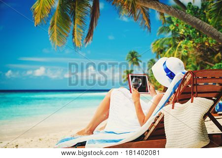 woman with touch pad on tropical beach, vacation concept