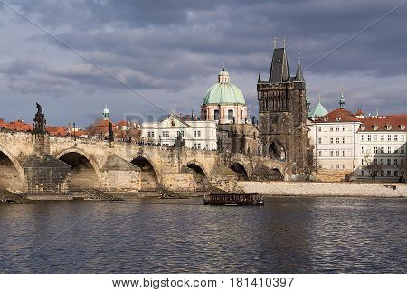 The Charles Bridge with many visitors the Old Town Bridge Tower and a little boat on the river Vltava during a nice day