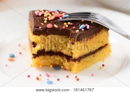 Low callorie bitten dessert pumpkin cake with chocolate icing and sugar confetti sprinkles closeup