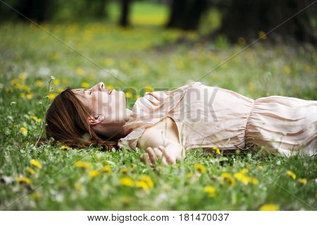 Beautiful young woman is lying on a sunspot spring field. Romantic conception.