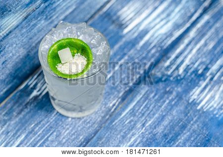 Transparent glass with tonic with ice and lime on a blue denim background