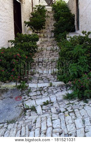 BERAT, ALBANIA - OCTOBER 01, 2016: Narrow cobble stone street with traditional ottoman white stone houses in Old town Berat, Albania on October 01, 2016.