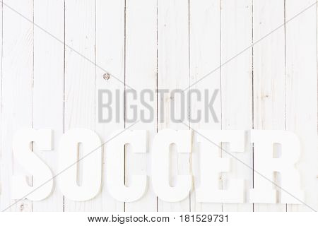 White letters Soccer on a painted white woood boards.