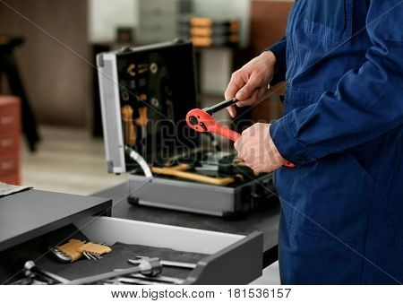 Auto mechanic with tools in car repair shop