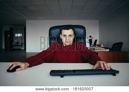 Young handsome hipster man running the office at the computer.