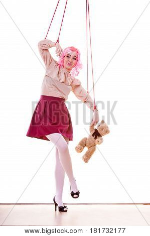 Mental disorder concept. Young woman girl stylized like marionette puppet on string with teddy bear toy isolated on white background