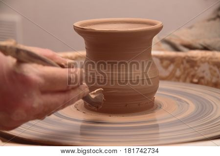 hands of a potter, creating an earthen jar on a pottery wheel