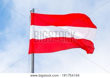 Flag of Austria waving in sunny and cloudy sky