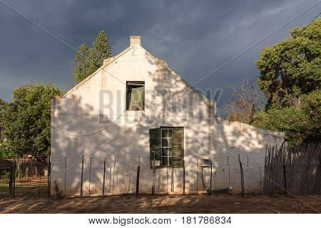 DE RUST SOUTH AFRICA - MARCH 23 2017: An historic old house in De Rust against a backdrop of dark clouds