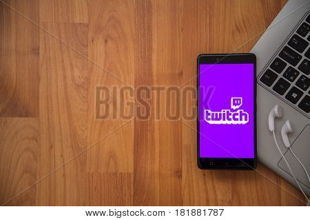 Los Angeles, USA, april 16, 2017: Twitch application on smartphone with earphones and notebook on wooden background.