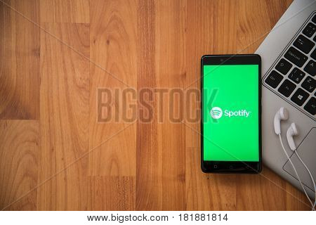 Los Angeles, USA, april 16, 2017: Spotify application on smartphone with earphones and notebook on wooden background.