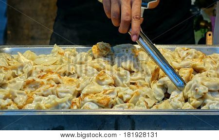 An outdoor vendor sells fried dumplings or pot-stickers