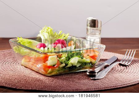 Fresh vegetables salad in a glass bowl. Mix from the cut radish pomidory and cucumbers. Close up selective focus