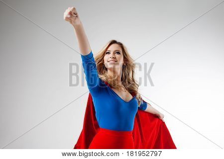 Superhero Woman. Young and beautiful blonde in the image of a super heroine in a red Cape