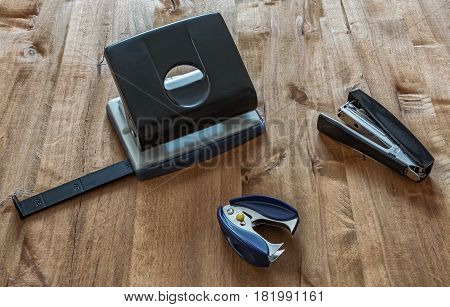 On the wooden surface are a stapler anti-stapler and puncher