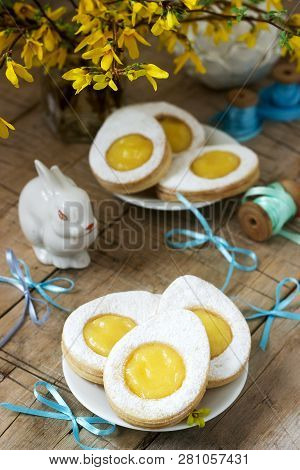 Easter Composition With Egg-shaped Cookies Filled With Lemon Curd, Rabbit, Bouquet Of Forsythia And 