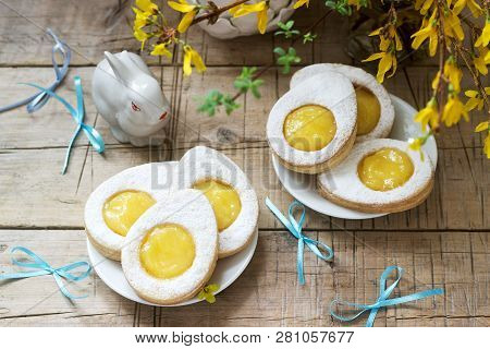 Easter Composition With Egg-shaped Cookies Filled With Lemon Curd, Rabbit, Bouquet Of Forsythia And 