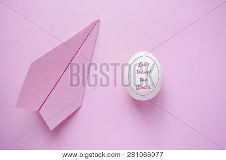 A White Single Egg On Pink Background With Paper Plane And Copyspace. Travel Concept.