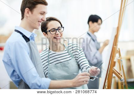Portrait Of Female Art Teacher Helping Student Painting Picture On Easel During Class, Copy Space
